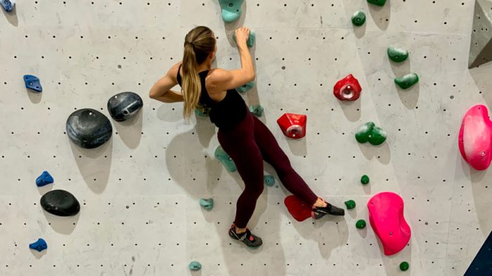Woman hanging from holds on a bouldering wall