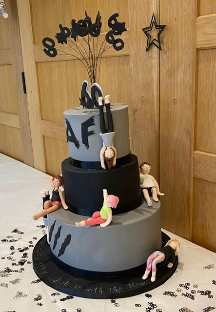 A three-tiered grey and black birthday cake featuring Animal Flow claw marks and marzipan Flowists