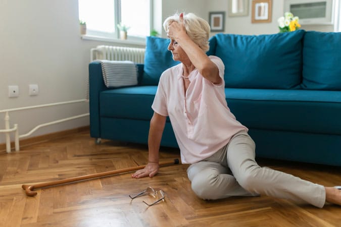 Elderly woman on the floor in front of a blue couch