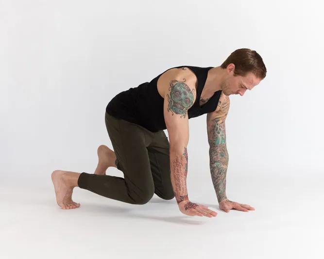 Man in Beast position, with opposite hand and foot hovering above the ground